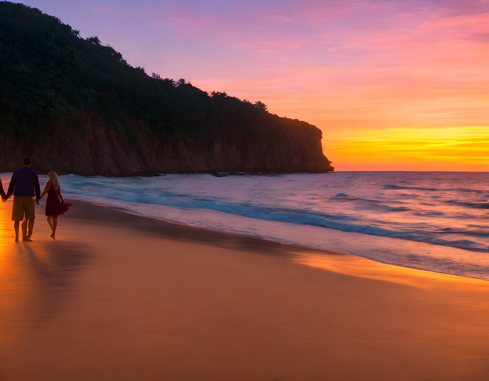 Couple walking on beach at sunset with orange and pink skies