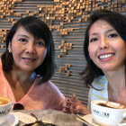 Two women with gold facial adornments in front of a mechanical backdrop.