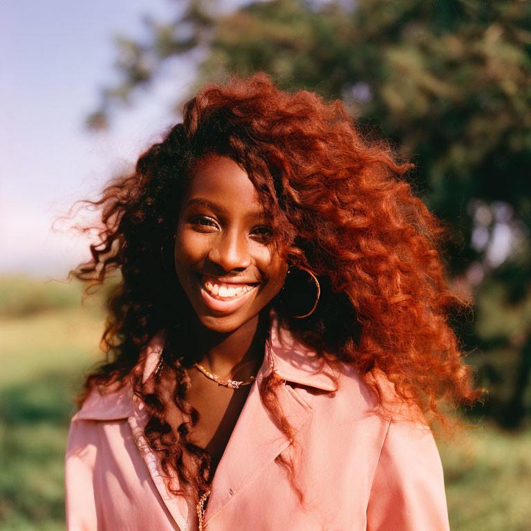 Curly-Haired Woman in Pink Jacket Outdoors with Trees