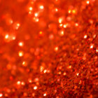 Close-up Image of Red and Orange Glitter Sparkling with Light Reflections