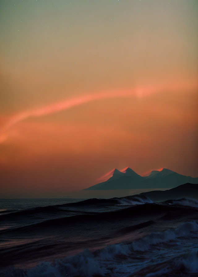 Twilight beach scene with waves and mountain silhouette