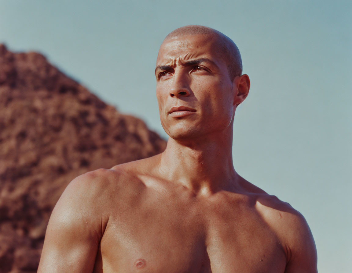 Serious bald man with mountain backdrop