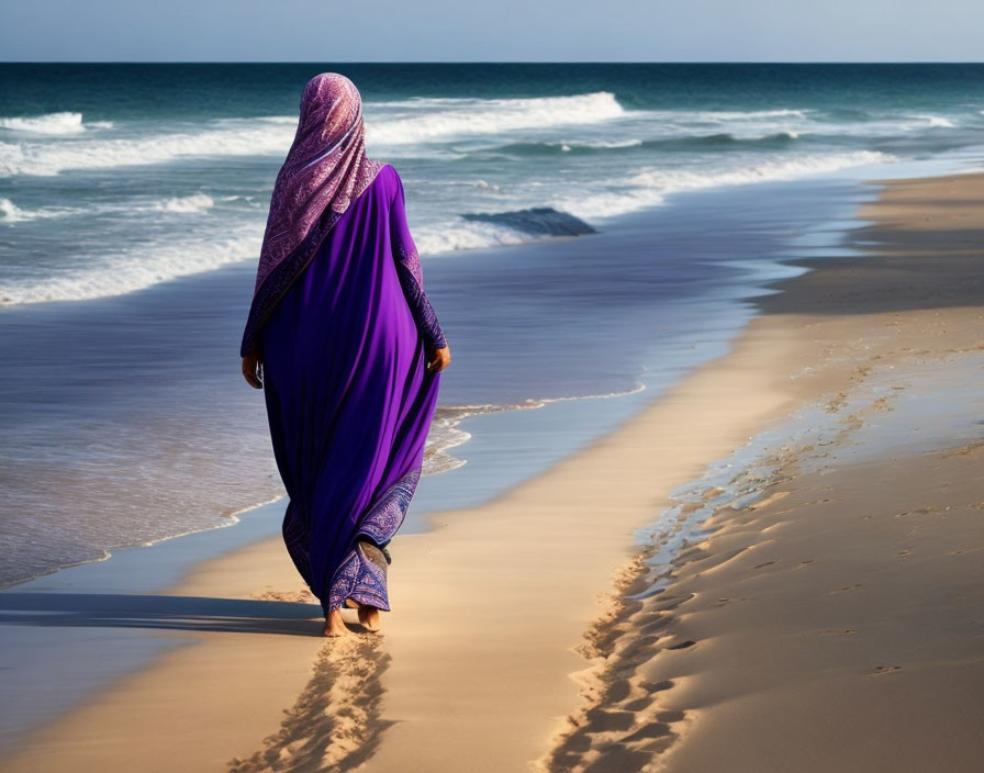 Person in purple garment strolling on sandy beach by the sea