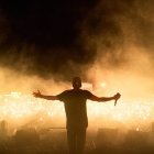 Performer with outstretched arms in front of cheering crowd at night show