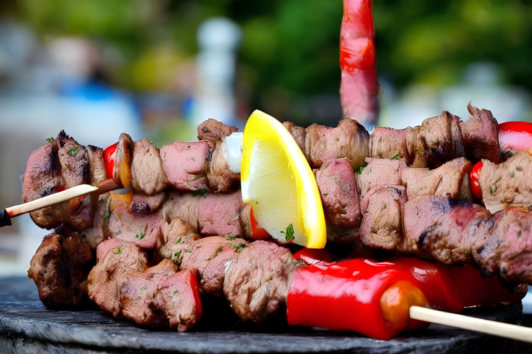 Slate background with grilled kebab skewers, meat chunks, lemon, and chili pepper