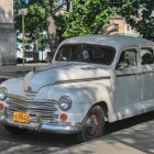 Classic Car Parked on Rainy City Street at Twilight with Person Holding Umbrella