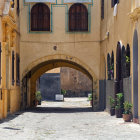 Whimsical painting of anthropomorphic animals in medieval attire on sunlit cobblestone street