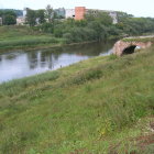 Medieval scene with stone bridge, castle, tents, people in historical clothing, river, lush green