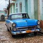 Classic blue car in colorful old town street scene.