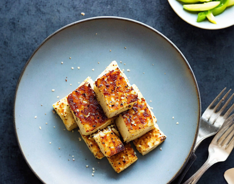 Grilled Golden-Brown Tofu Slices with Sesame Seeds on Blue Plate