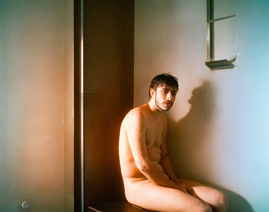 Contemplative person bathed in soft light in a shadowy bathroom