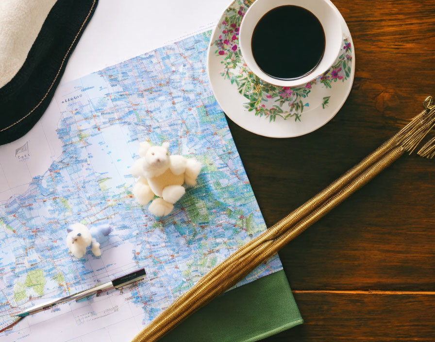 Travel-themed flat lay with map, coffee cup, notebook, pen, plush toys, and golden wand