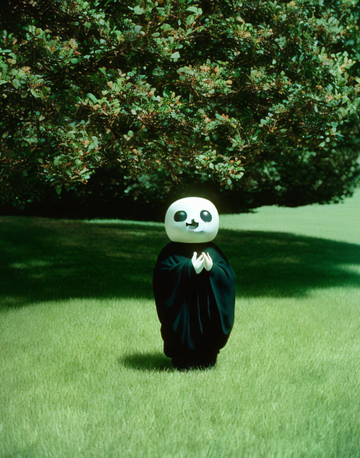 Person in panda costume standing on grass with hands together in front of bush