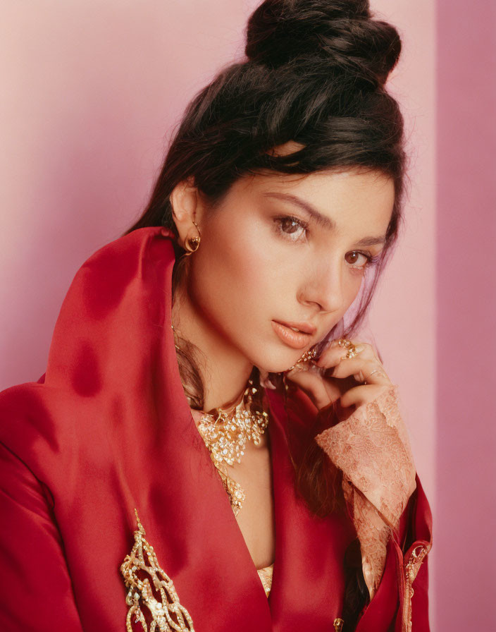 Woman with Top Bun Hairstyle in Red Shawl and Golden Jewelry on Pink Background