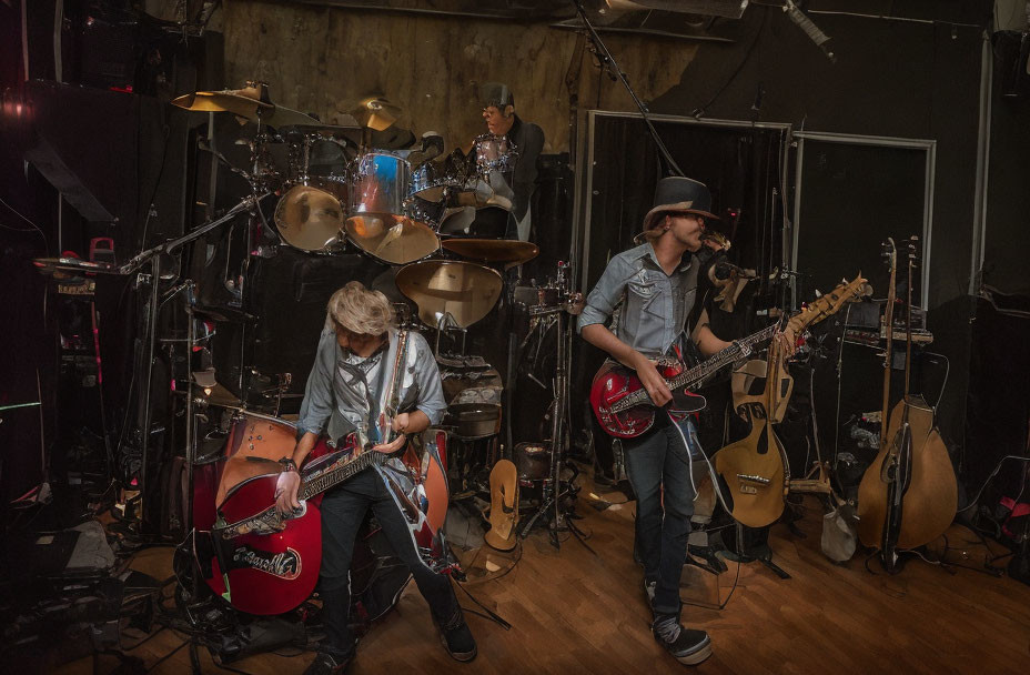 Musicians with guitars and drums in dimly lit studio