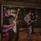 Musicians with guitars and drums in dimly lit studio