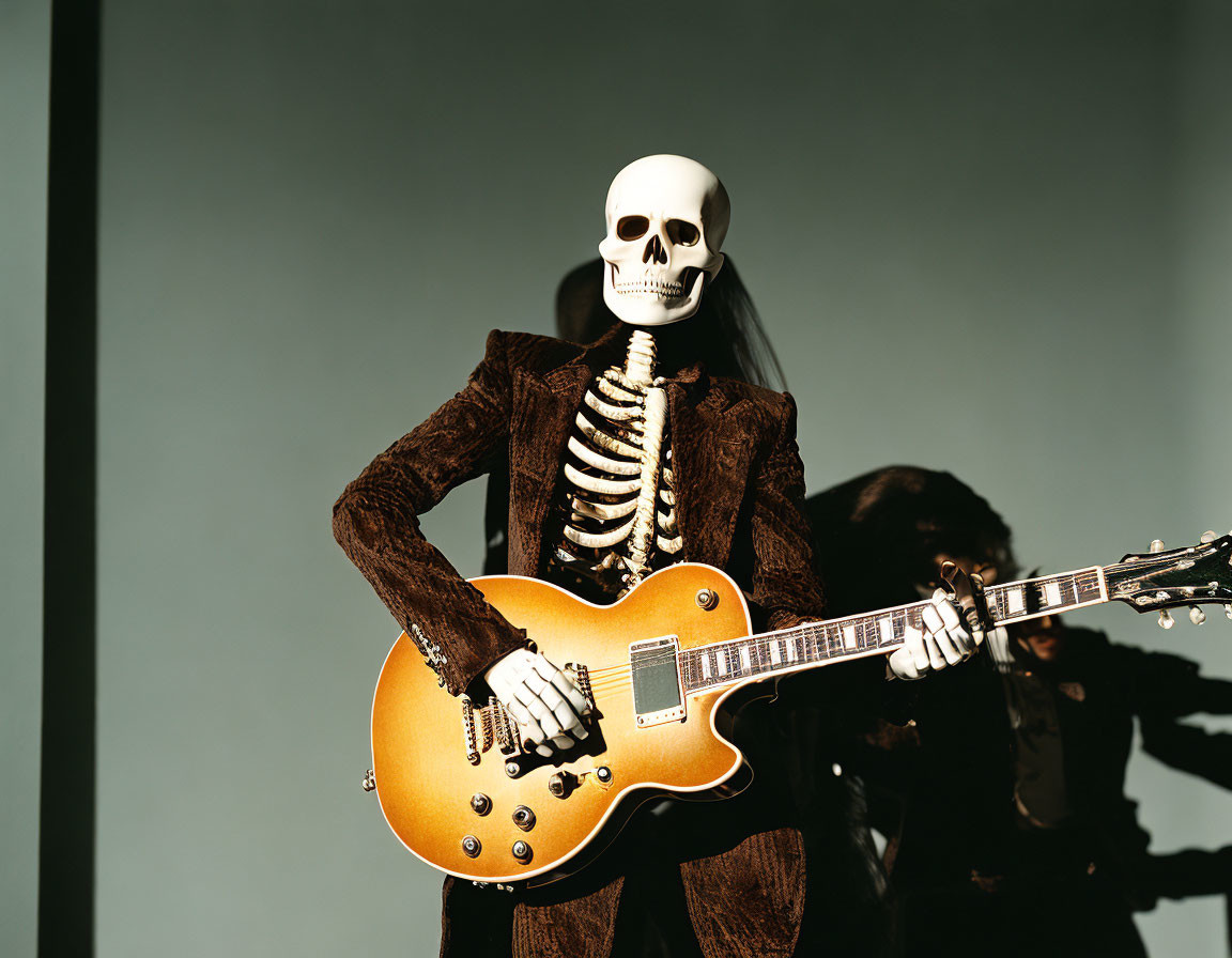 Skeleton model in brown suit plays sunburst electric guitar with shadowy figure