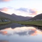 Tranquil sunset scene with small boats and fisherman on calm lake