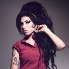 Woman with Large Beehive Hairstyle and Tattoos Poses on Grey Background