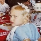 Child with Blue Eyes and White Hair in Light Blue Shirt Surrounded by Flowers and Sweets