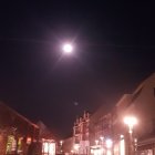 Traditional cobblestone street at night with warm lights and detailed moon.