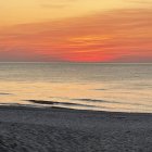 Young girl on beach gazes at vibrant ocean sunset