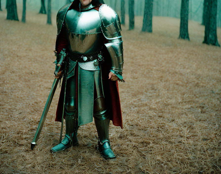 Medieval knight in full armor with sword and red cape in forest