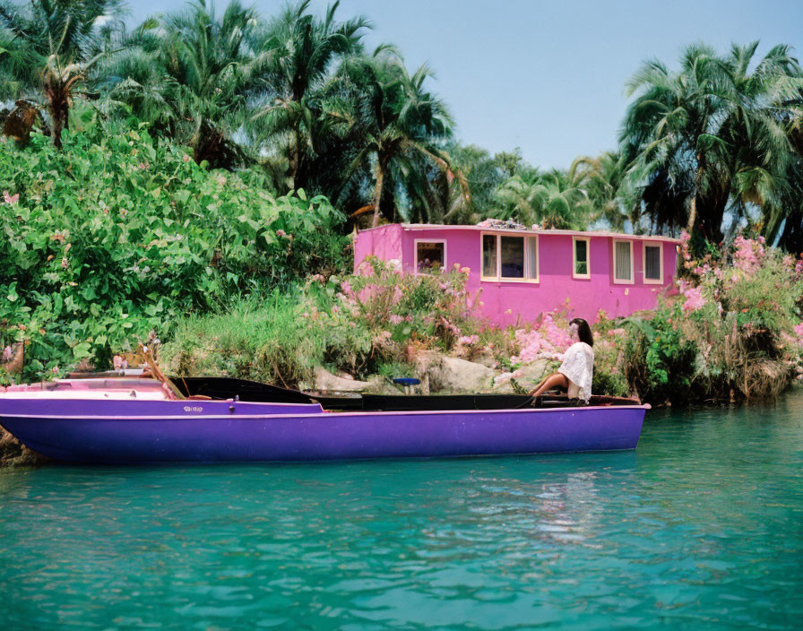 Person in Purple Canoe by Riverbank with Pink House & Flowers