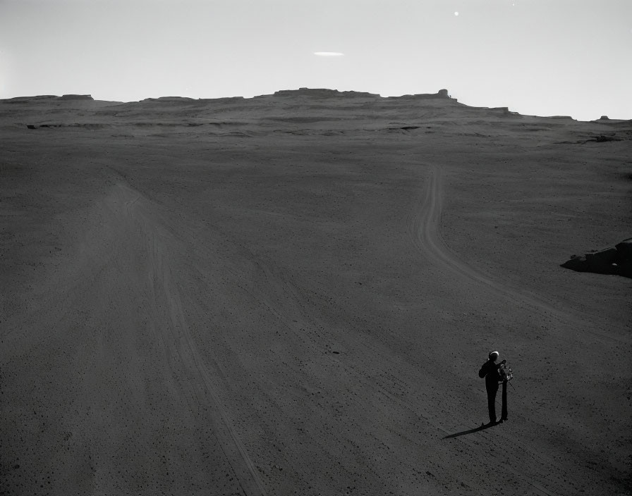 Barren landscape with solitary figure under vast sky