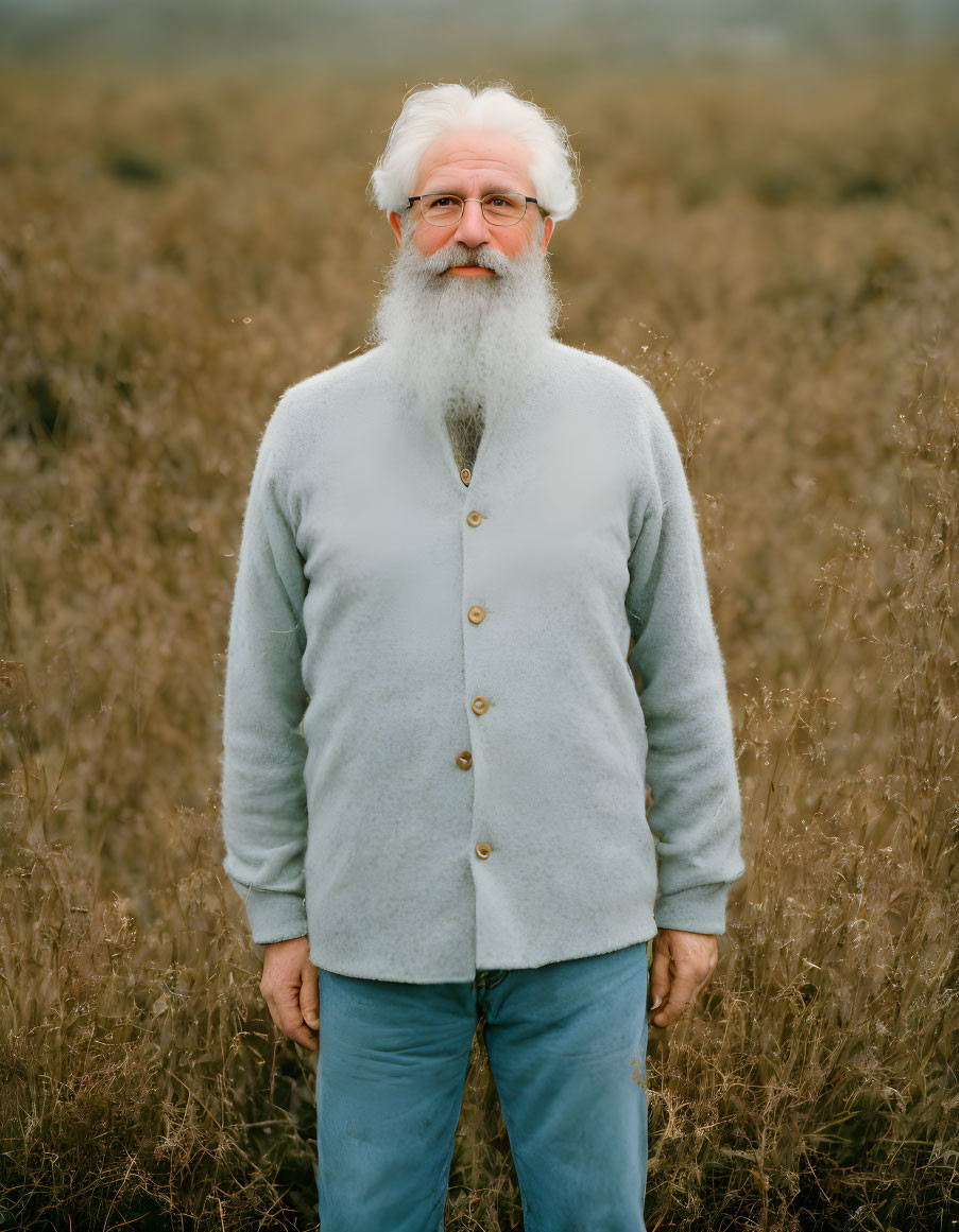 Elderly man with white beard and glasses in field with tall dry grass