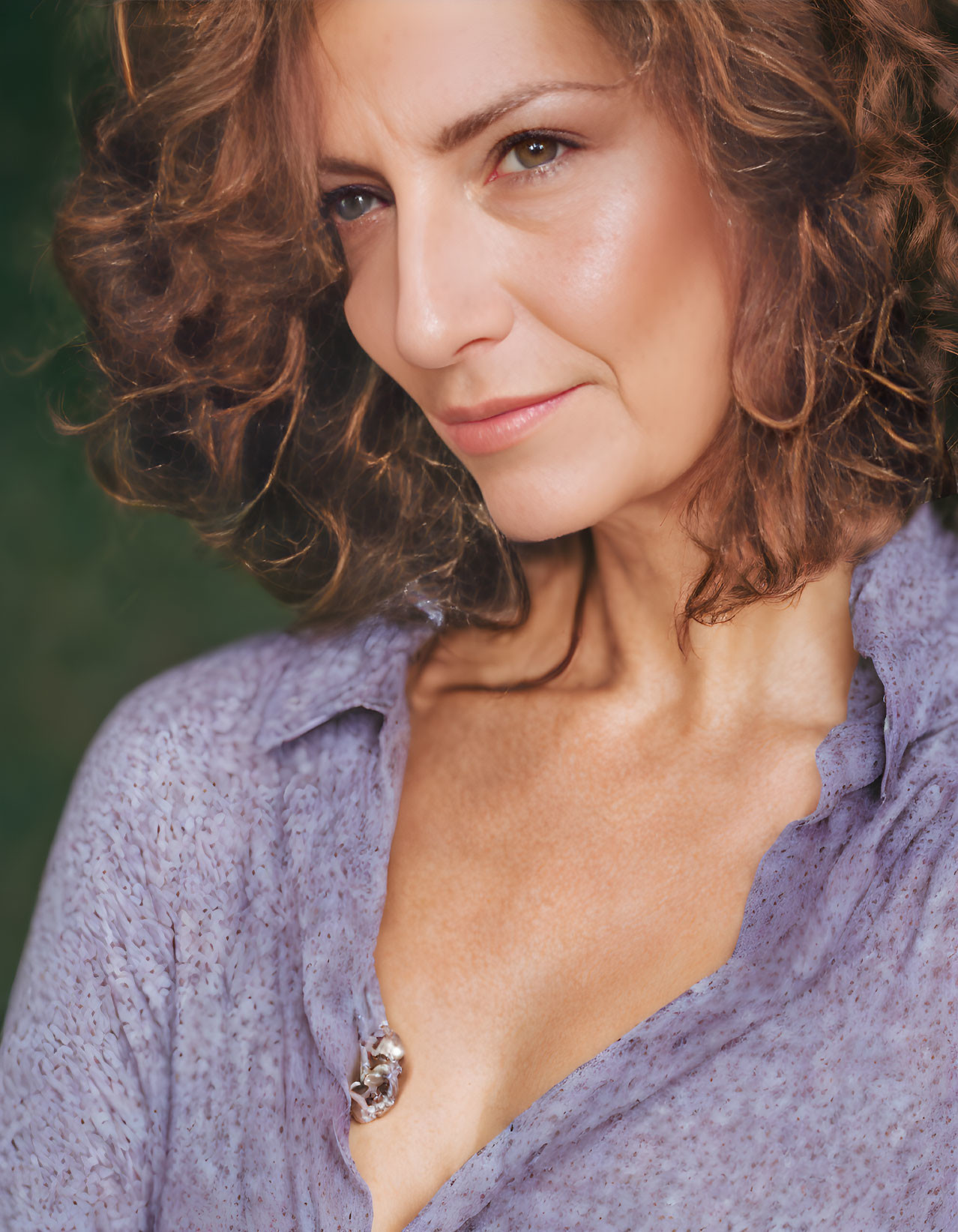 Curly-haired woman in purple blouse with brooch portrait.