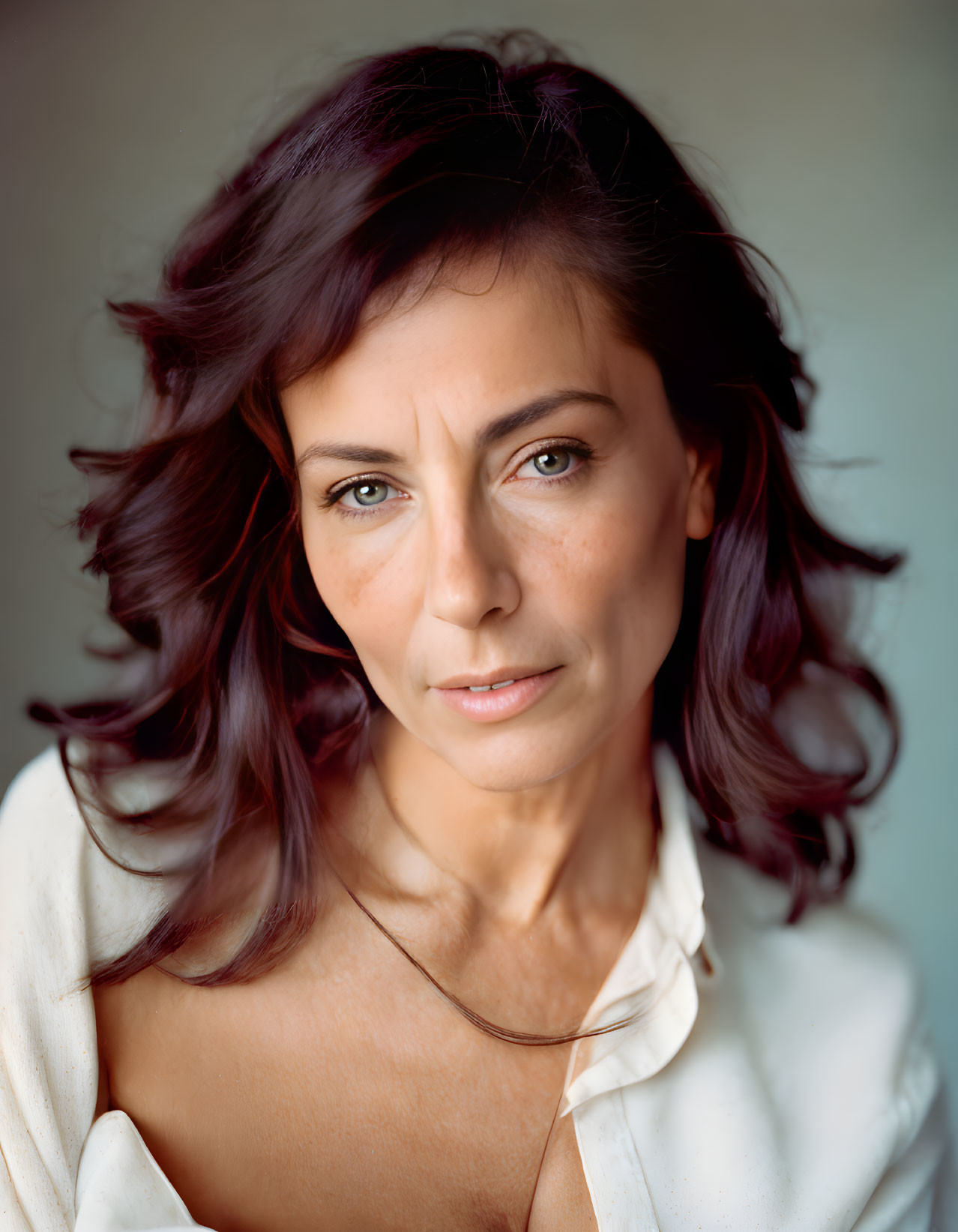 Auburn-Haired Woman in White Blouse with Blue Eyes and Soft-Focus Background