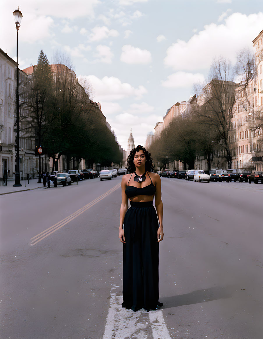 Woman in empty city street with classic architecture under cloudy sky