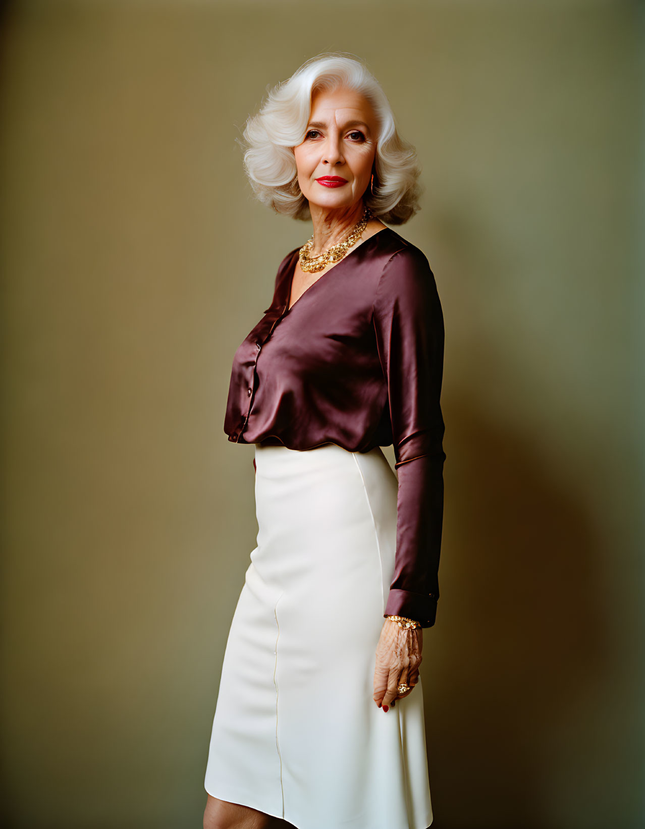 Senior Woman in Stylish Brown Blouse and White Skirt on Neutral Background