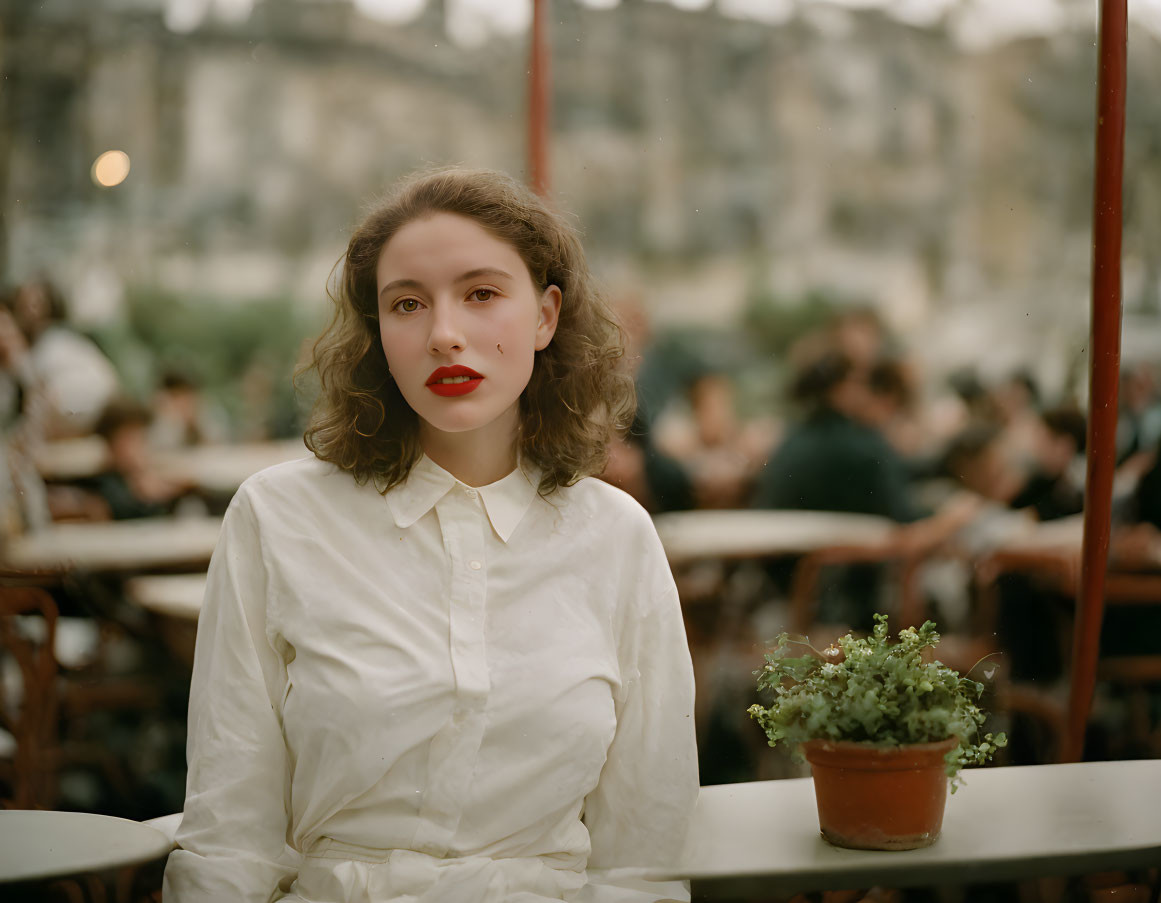 Woman in red lipstick at cafe with blurred background.