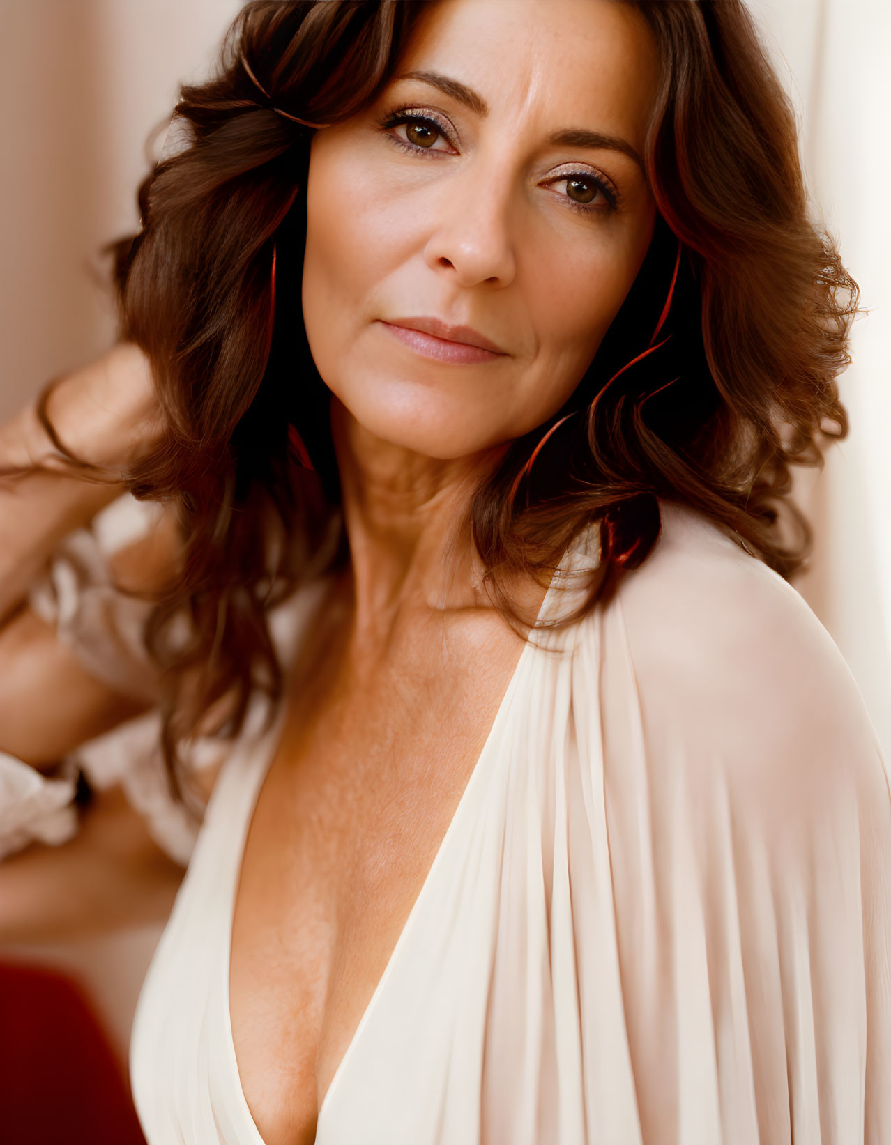 Dark Curly-Haired Woman in White Plunging Top on Warm Background