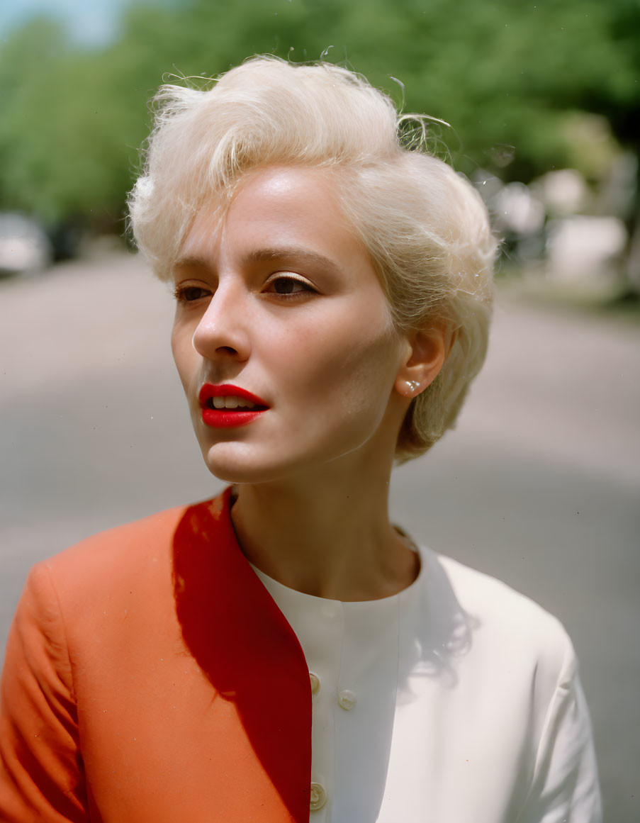 Blonde woman in white blouse and orange blazer outdoors