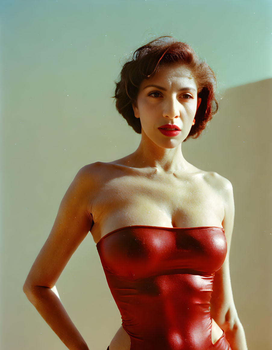 Short-Haired Person in Red Strapless Top Against Plain Background