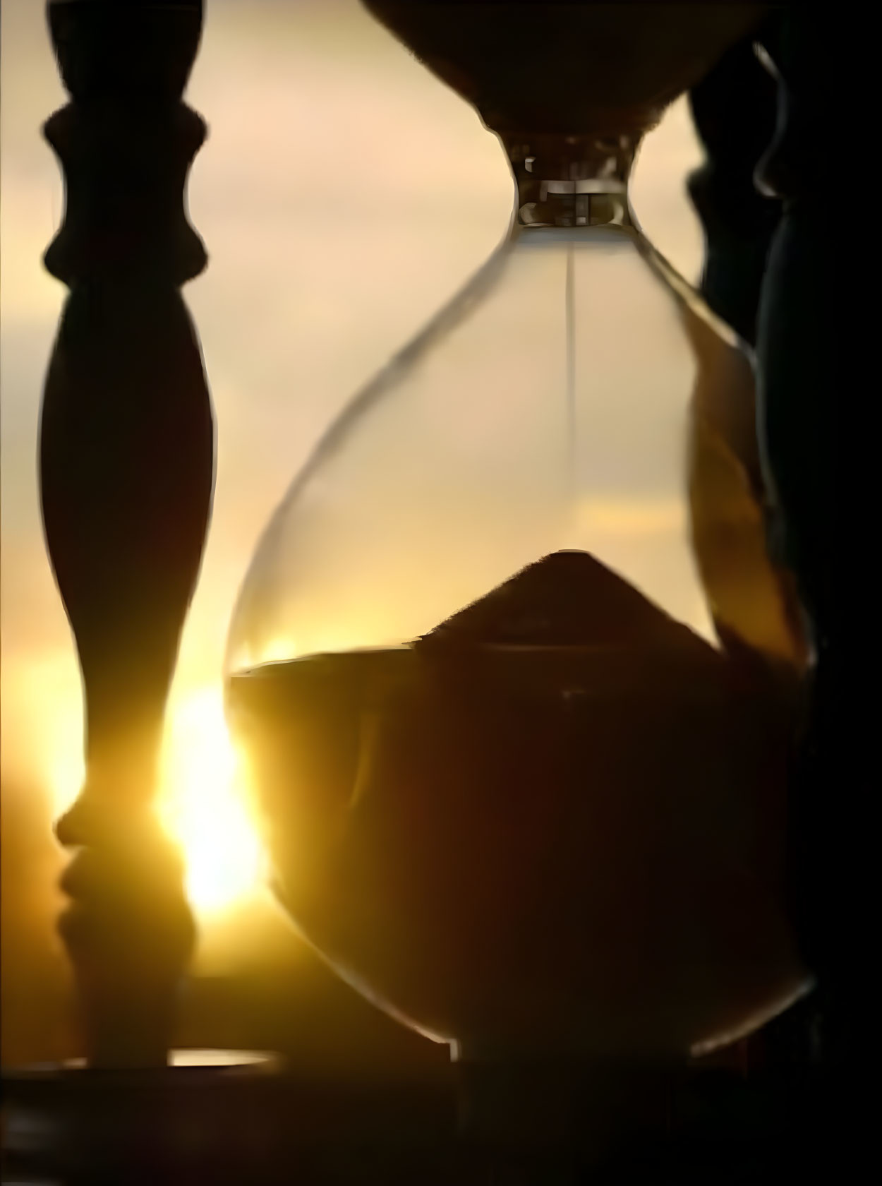 Hourglass with flowing sand against warm sunset backdrop