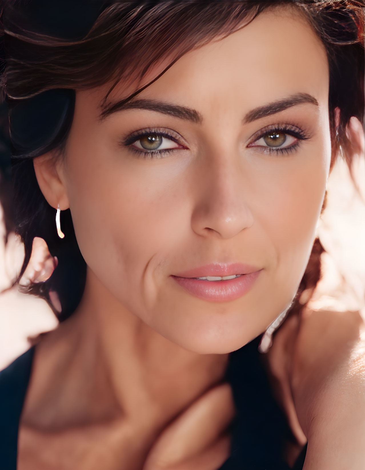 Portrait of woman with olive skin, hazel eyes, dark hair in messy updo, subtle makeup