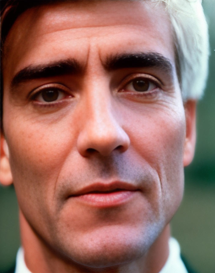 Portrait of man with graying hair and intense eyes on green background