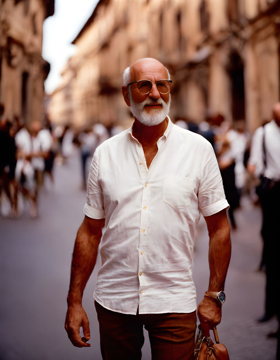 Elderly man with beard and glasses smiling on city street.