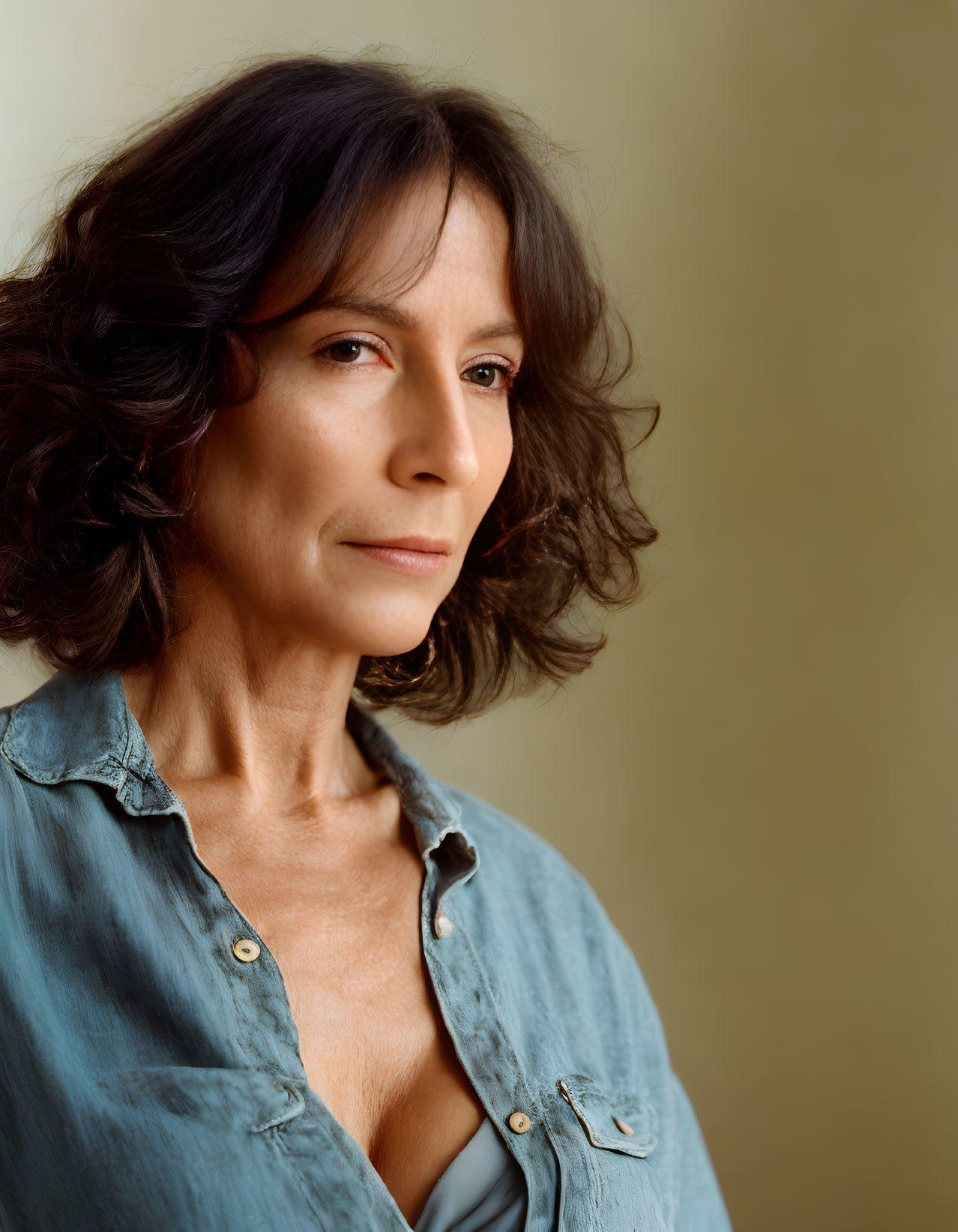 Woman with Brown Hair in Blue Shirt Against Beige Background