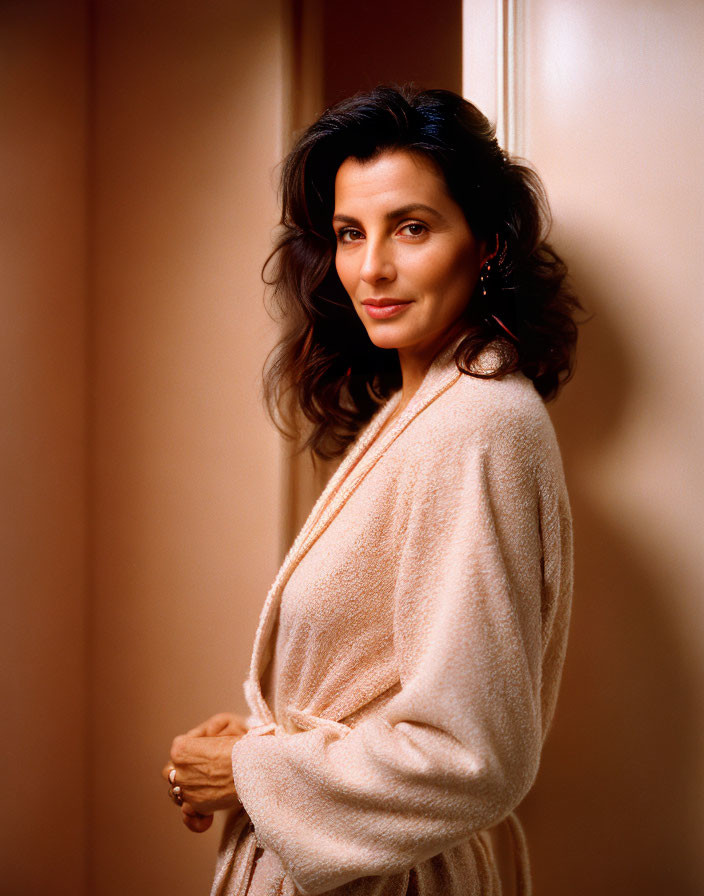 Dark-haired woman in light cardigan against beige background