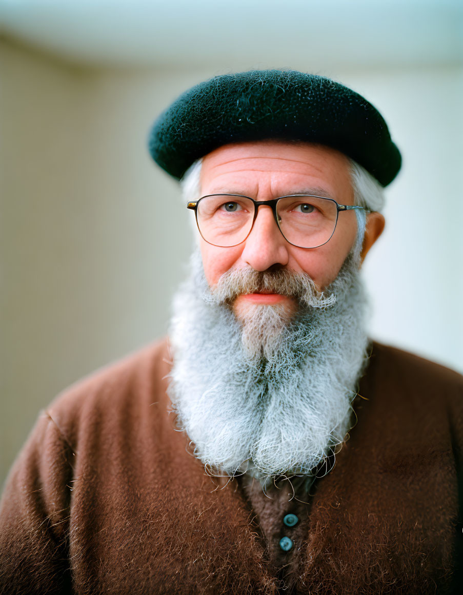 Elderly man with gray beard, green beret, and spectacles in brown sweater