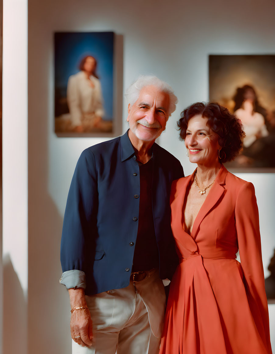 Elderly Couple Smiling in Blue and Orange Outfits Among Room Paintings