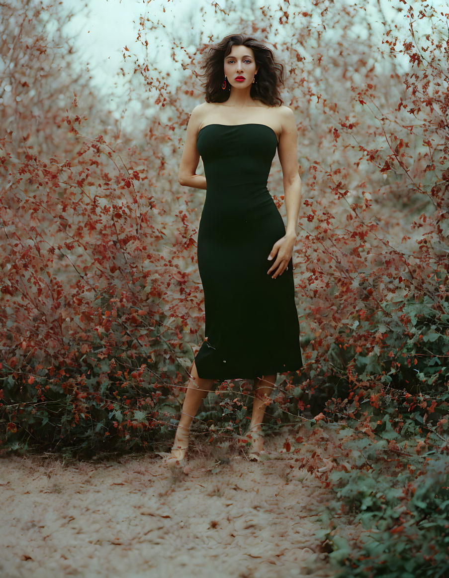 Woman in strapless green dress surrounded by autumn foliage and falling leaves.