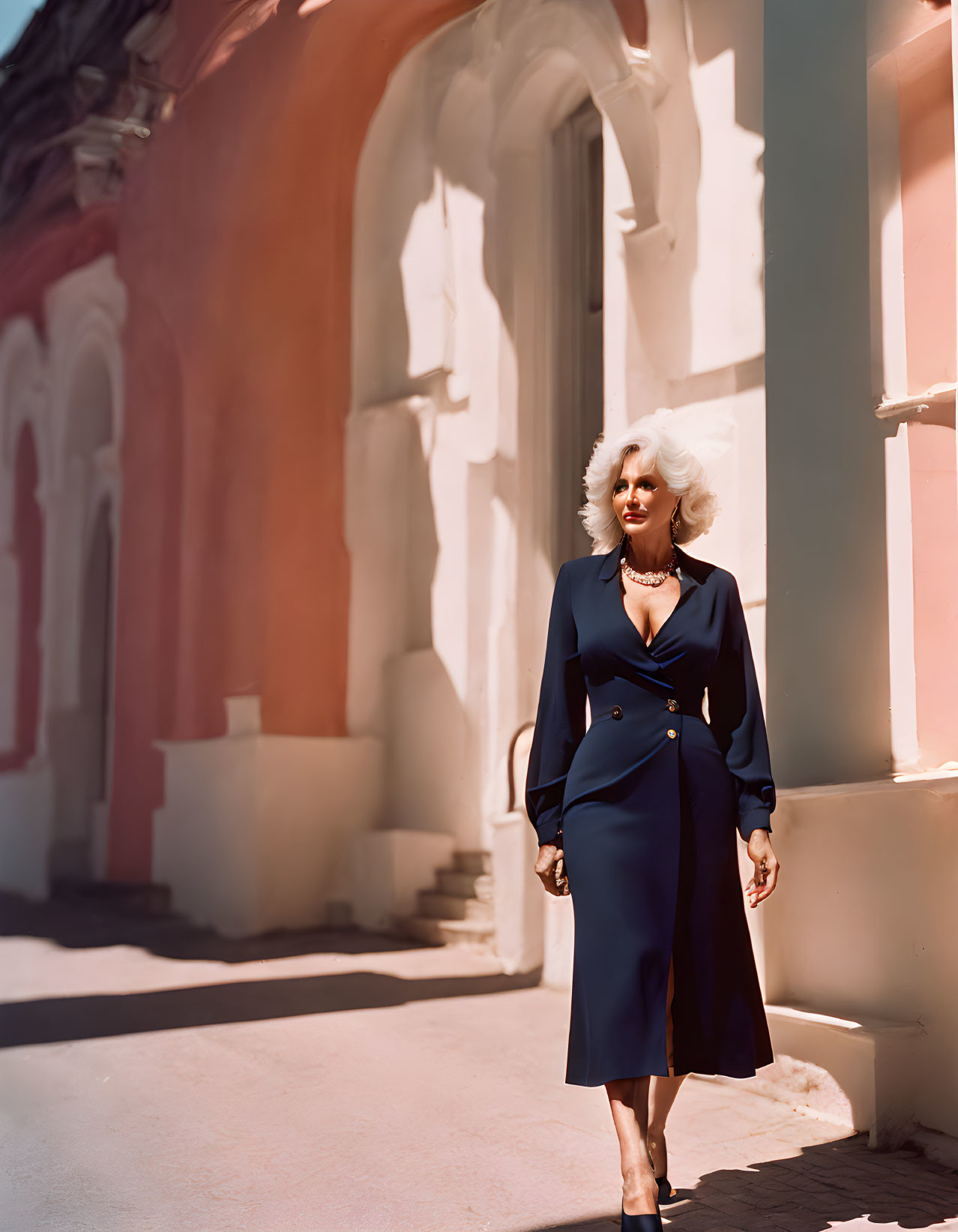 White-Haired Woman in Blue Dress Stands by Ornate Building