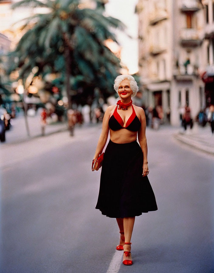 Smiling woman in vintage black and red outfit on city street with buildings and palm tree.