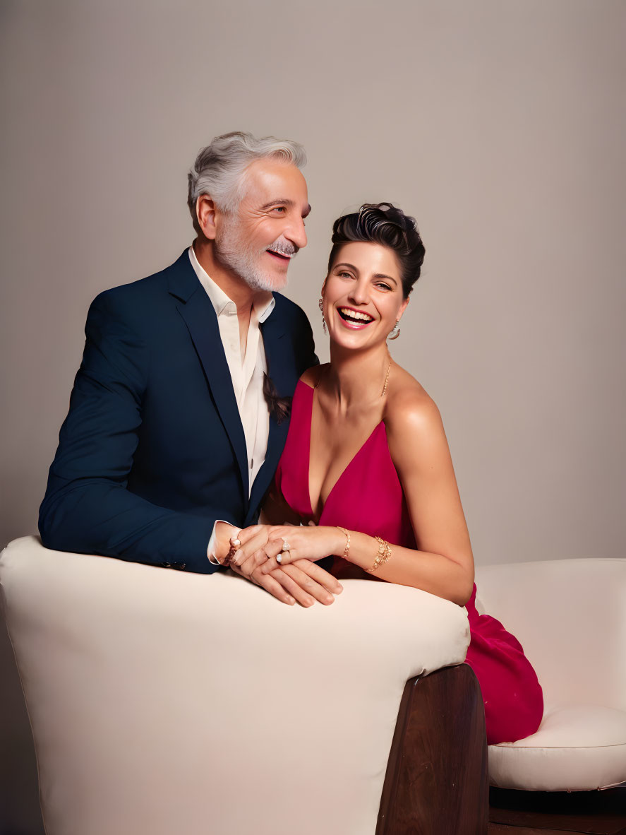 Smiling couple in blue suit and red dress on white couch